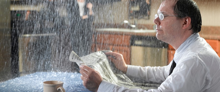 Man reading paper in flooded kitchen