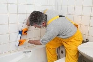 plumber caulking a bathtub
